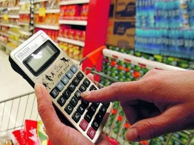 Cliente calcula preços em supermercado no Brasil, refletindo a diferença entre IPCA e inflação do dia a dia.