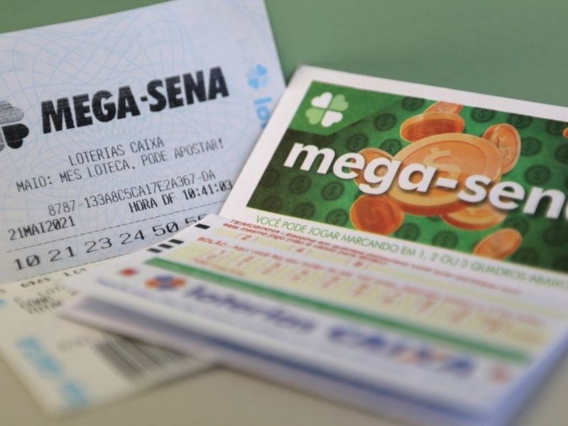 Volantes e bilhetes da Mega-Sena sobre mesa, representando o prêmio acumulado