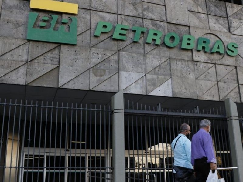 Fachada da Petrobras com logotipo da estatal e pessoas caminhando em frente ao prédio