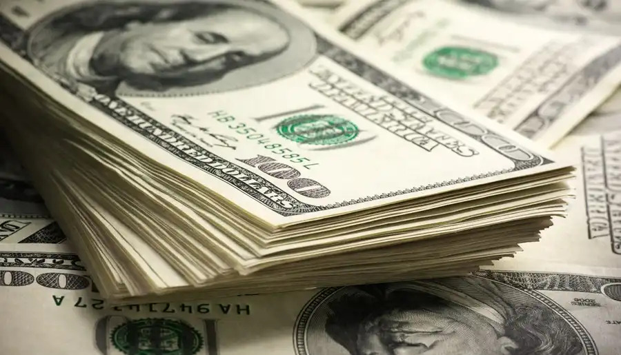 Cédulas de dólar americano empilhadas, simbolizando o comportamento do câmbio e a valorização da moeda dos EUA frente ao real.