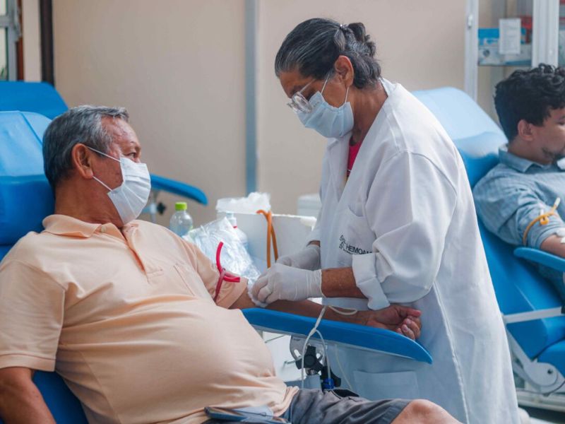 Homem, em um hemocentro, sendo atndido por uma enfermeira, no momento da doação de sangue
