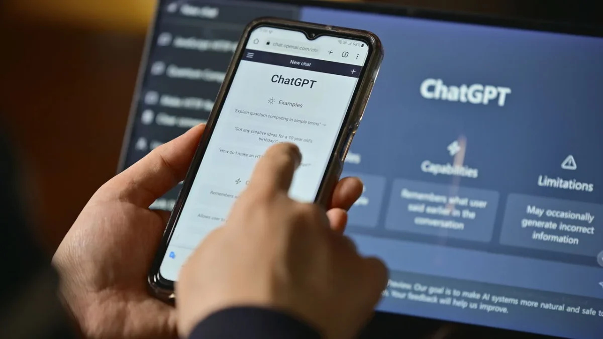 Pessoa utilizando o ChatGPT em smartphone; tela do sistema de inteligência artificial exibe comandos e funções.