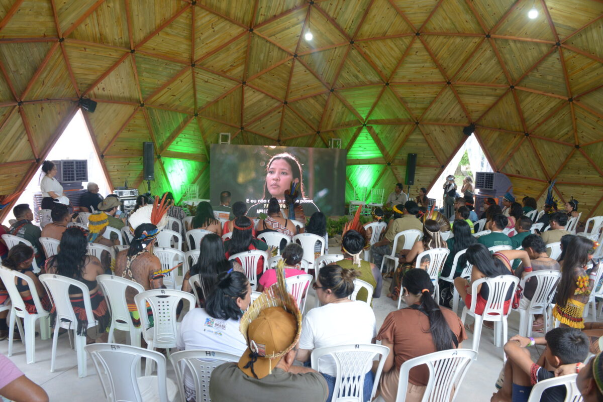 Lideranças indígenas assistem a uma plenária na Aldeia COP, estrutura montada na Universidade Federal do Pará durante a COP30, com debates sobre justiça climática, segurança alimentar e demarcação de terras.