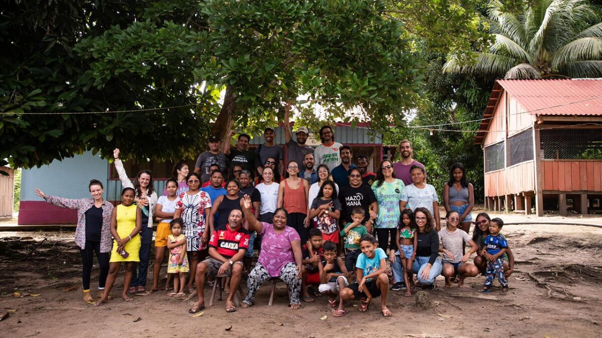 Grupo de moradores e representantes da Amaz Aceleradora reunidos em comunidade ribeirinha na Amazônia.