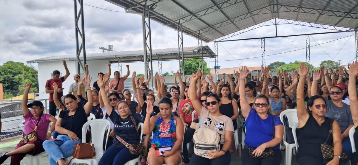 Professores reunidos em assembleia levantam as mãos para votar o fim da greve do magistério municipal em Manaus.