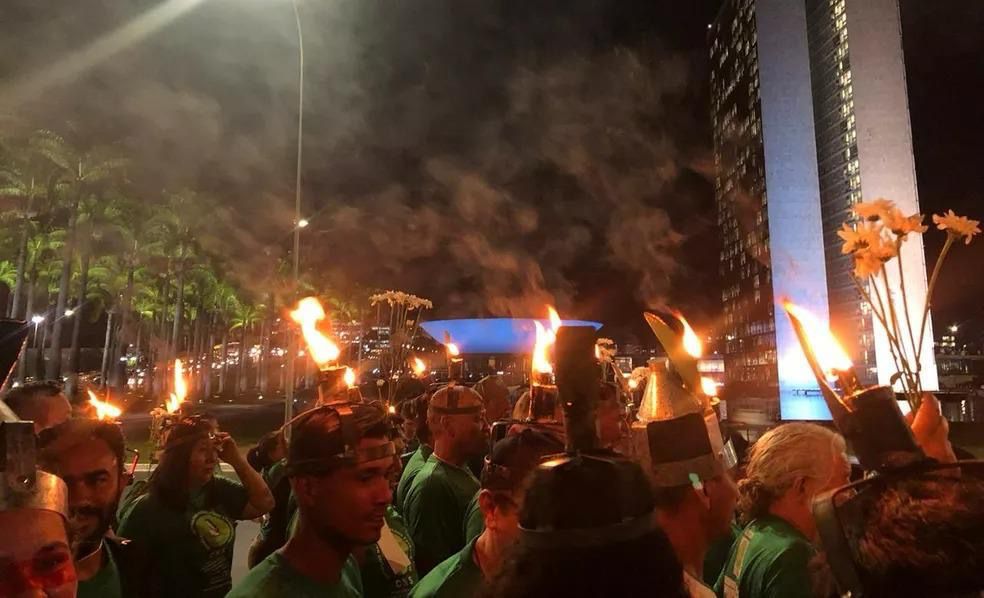 Lideranças dos povos da floresta marcham à noite com porongas acesas na cabeça, em ato simbólico que representa resistência e esperança durante a COP30.