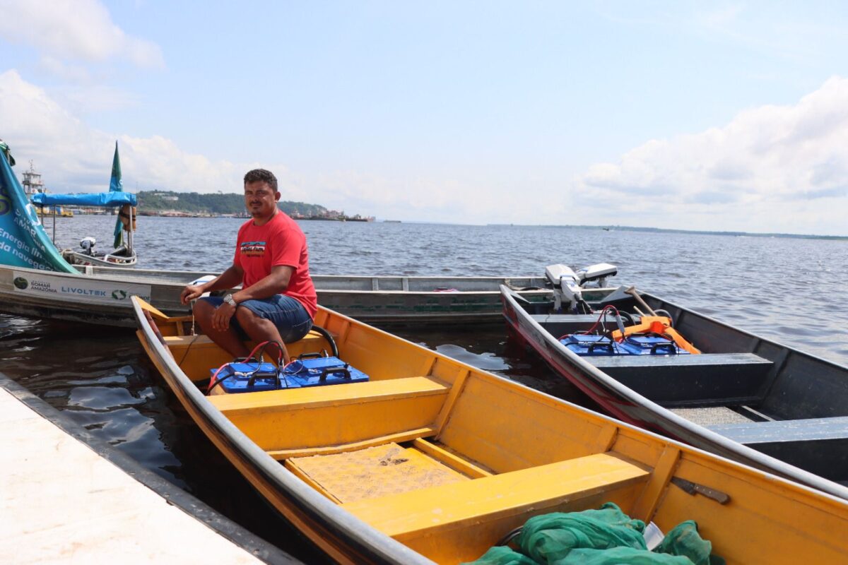 Pescador sentado em canoa com motor de rabeta elétrica no rio em Careiro da Várzea.