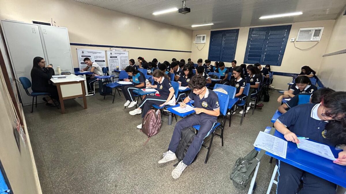 Estudantes em sala de aula participam de atividade escrita sob supervisão de professora em Manaus.
