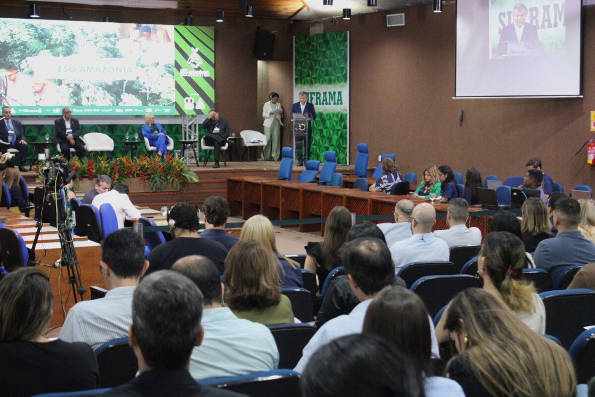 Público acompanha o 1º Encontro ZFM+ESG no auditório da Suframa, com apresentações no palco e painel sobre sustentabilidade.