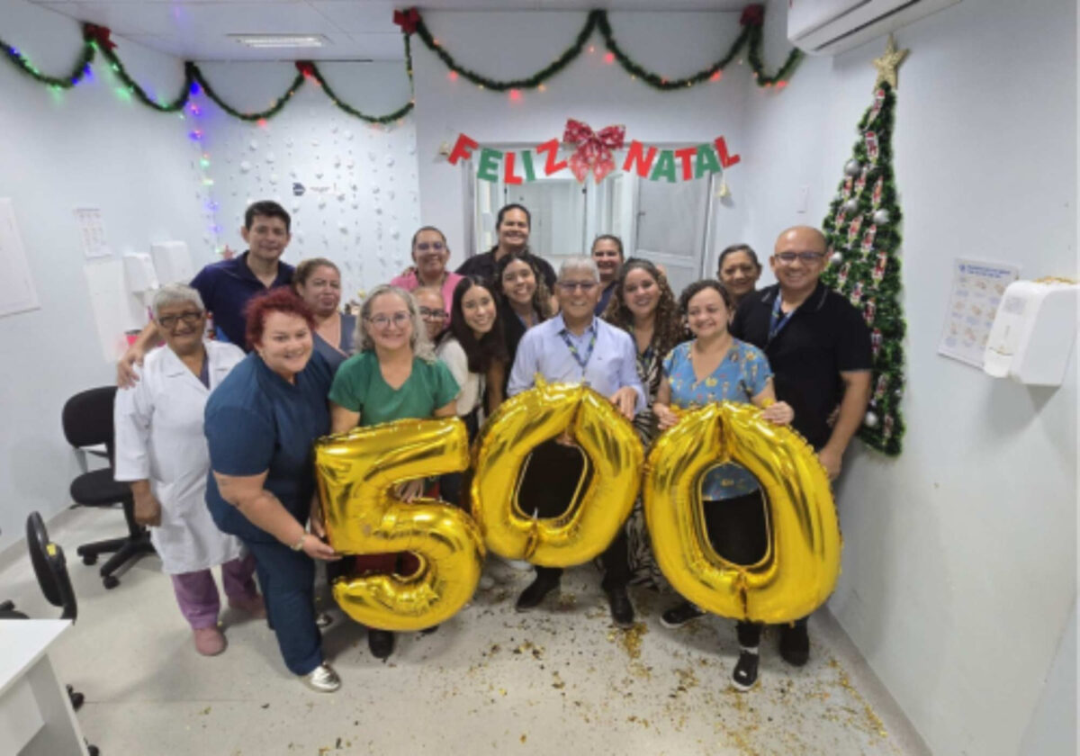 Equipe da Fundação Hospitalar Alfredo da Matta reunida em centro cirúrgico durante mutirão do Opera+ Amazonas, segurando balões com o número 500.
