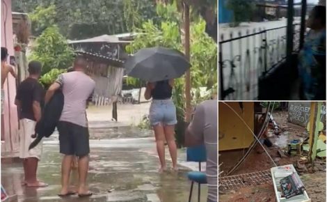 Moradores enfrentam chuva intensa e alagamento em área residencial, com casas atingidas pela água.