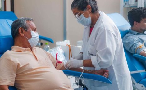 Homem, em um hemocentro, sendo atndido por uma enfermeira, no momento da doação de sangue