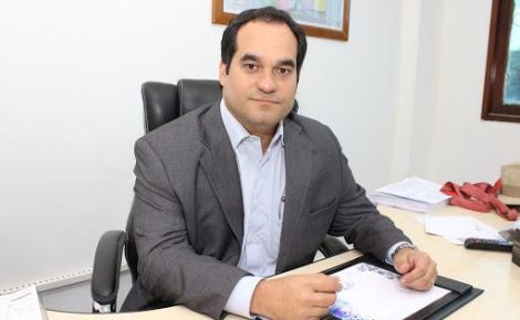 Flávio Antony Filho sentado à mesa de trabalho no gabinete da Casa Civil do Amazonas, com documentos e caneta à frente.