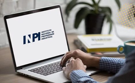 Logotipo do INPI exibido na tela de um notebook sobre mesa de trabalho.