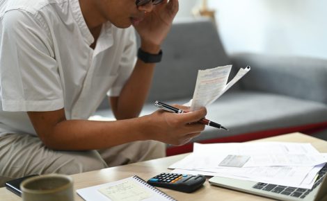Pessoa calculando contas em casa, representando a inadimplência no Amazonas em 2025.