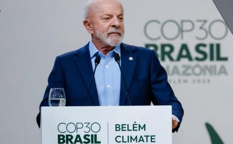 Presidente Lula fala em púlpito diante de bandeiras internacionais durante a abertura da Cúpula do Clima em Belém, no auditório principal do evento.
