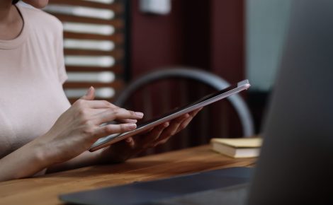 a asian female student sitting at the table, using tablet when studying online at home