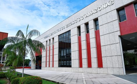 Fachada do prédio do Tribunal de Contas do Estado do Amazonas (TCE-AM), em Manaus, com palmeira e jardim em primeiro plano.