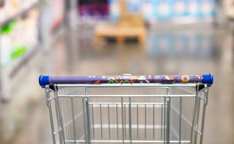 abstract blurry photo of a supermarket with an empty shopping cart concept.