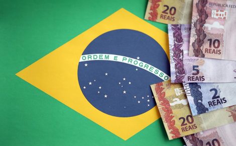 brazilian money bills on top of the national flag of federative republic of brazil