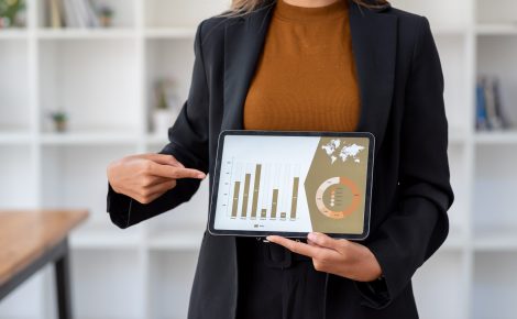 businesswoman holding tablet with financial charts and data analysis on the screen in an office setting.
