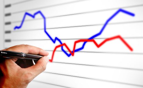 close up of hand holding pen drawing a business graph on laptop