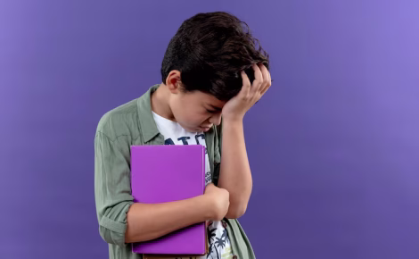 com a cabeca baixa o menino triste segurando o livro e colocando a mao na cabeca isolada na parede roxa com espaco de copia 141793 78749
