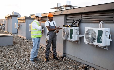 diverse workers with tablet fixing air conditioner on plant