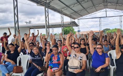 Professores reunidos em assembleia levantam as mãos para votar o fim da greve do magistério municipal em Manaus.