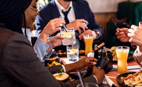 Pessoas bebem à mesa em bar, ilustrando consumo de bebidas alcoólicas no Brasil