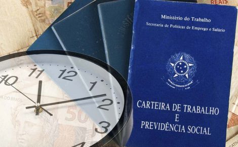 Carteira de trabalho ao lado de relógio e cédulas de dinheiro representa debate sobre jornada de trabalho no Brasil