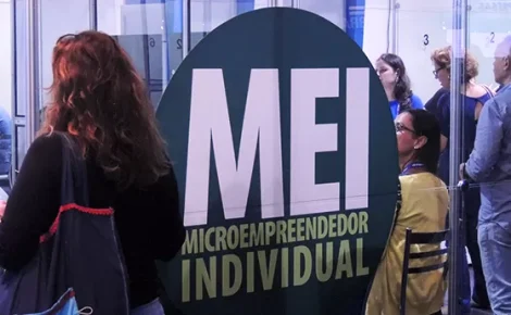 Pessoas em fila de atendimento diante de painel do Microempreendedor Individual, MEI