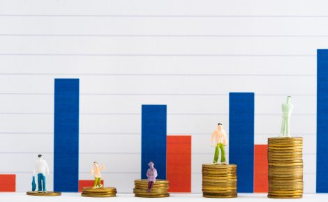 people figures on coins on white surface with graphs at background, concept of financial equality