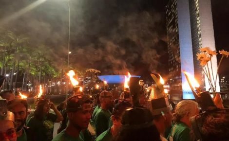 Lideranças dos povos da floresta marcham à noite com porongas acesas na cabeça, em ato simbólico que representa resistência e esperança durante a COP30.