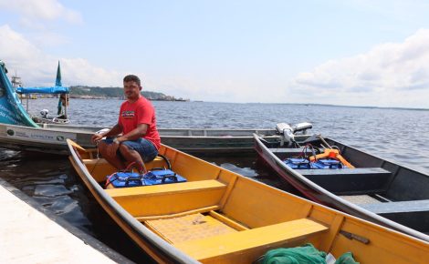 Pescador sentado em canoa com motor de rabeta elétrica no rio em Careiro da Várzea.
