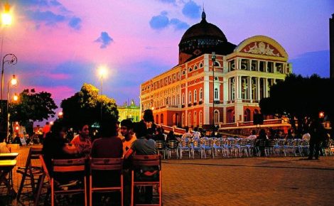 Teatro Amazonas ao entardecer com pessoas reunidas na Praça São Sebastião, em Manaus.