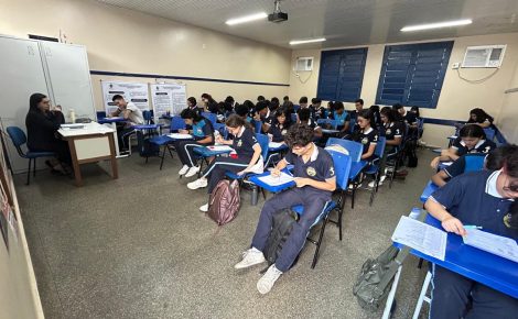 Estudantes em sala de aula participam de atividade escrita sob supervisão de professora em Manaus.
