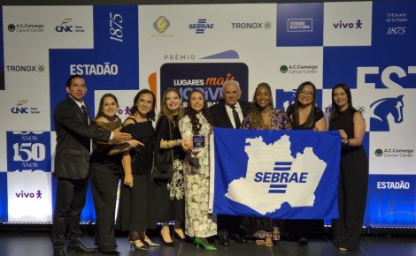 Grupo de colaboradores do Sebrae Amazonas posa sorridente segurando uma bandeira da instituição durante a premiação nacional em São Paulo.