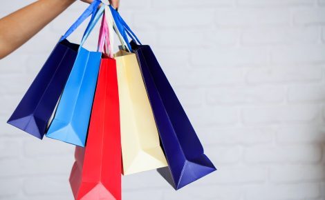 shopping. closeup of woman holding color paper shopping bag on white wall background