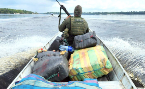 Policial armado transporta fardos de droga apreendidos em uma embarcação pelos rios da Amazônia