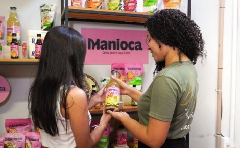 Duas mulheres observam produtos da Manioca em uma prateleira durante roteiro turístico da COP30.