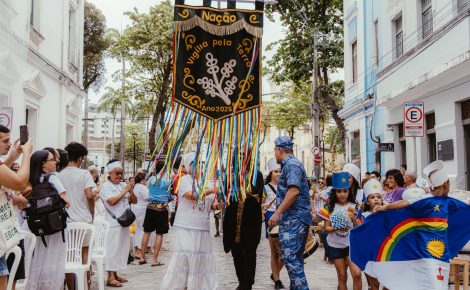 Lideranças religiosas, artistas e participantes seguram o estandarte “Nação – Vigília pela Terra 2025” durante ato inter-religioso em Belém, com fitas coloridas e trajes tradicionais.