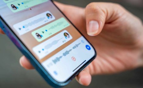 Pessoa segura celular exibindo tela com áudios de voz em aplicativo de mensagens.