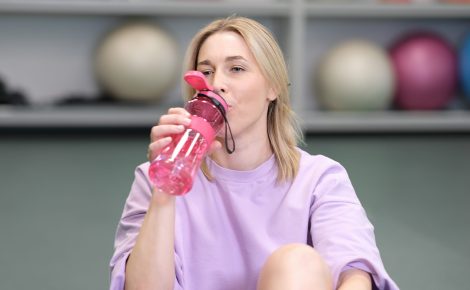 woman in a fitness center drinking water feeling tired and having a break during workout or training. workout with fitballs. healthy lifestyle